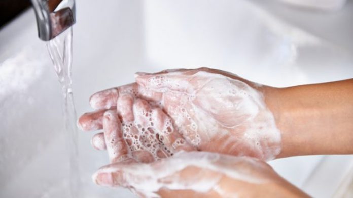 Woman washing her hands at the kitchen sink.