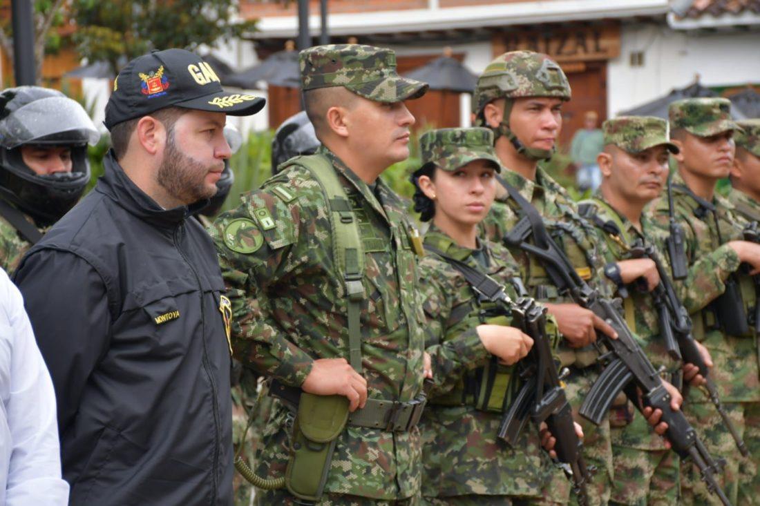 Militares con armas en la mano junto a persona con gorra negra